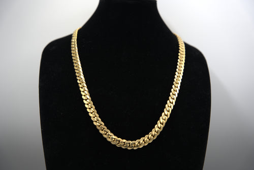 Gold chain necklace on a black mannequin against a white background