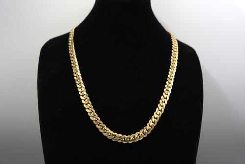 Gold chain necklace on a black mannequin bust against a white background