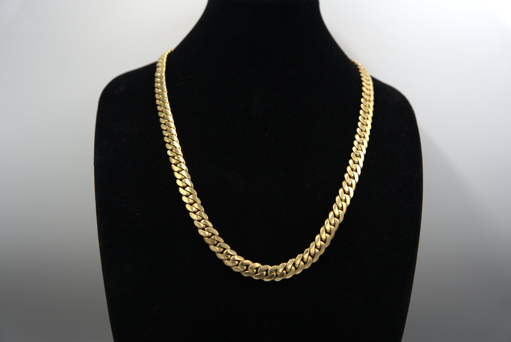 Gold chain necklace on a black mannequin bust against a white background