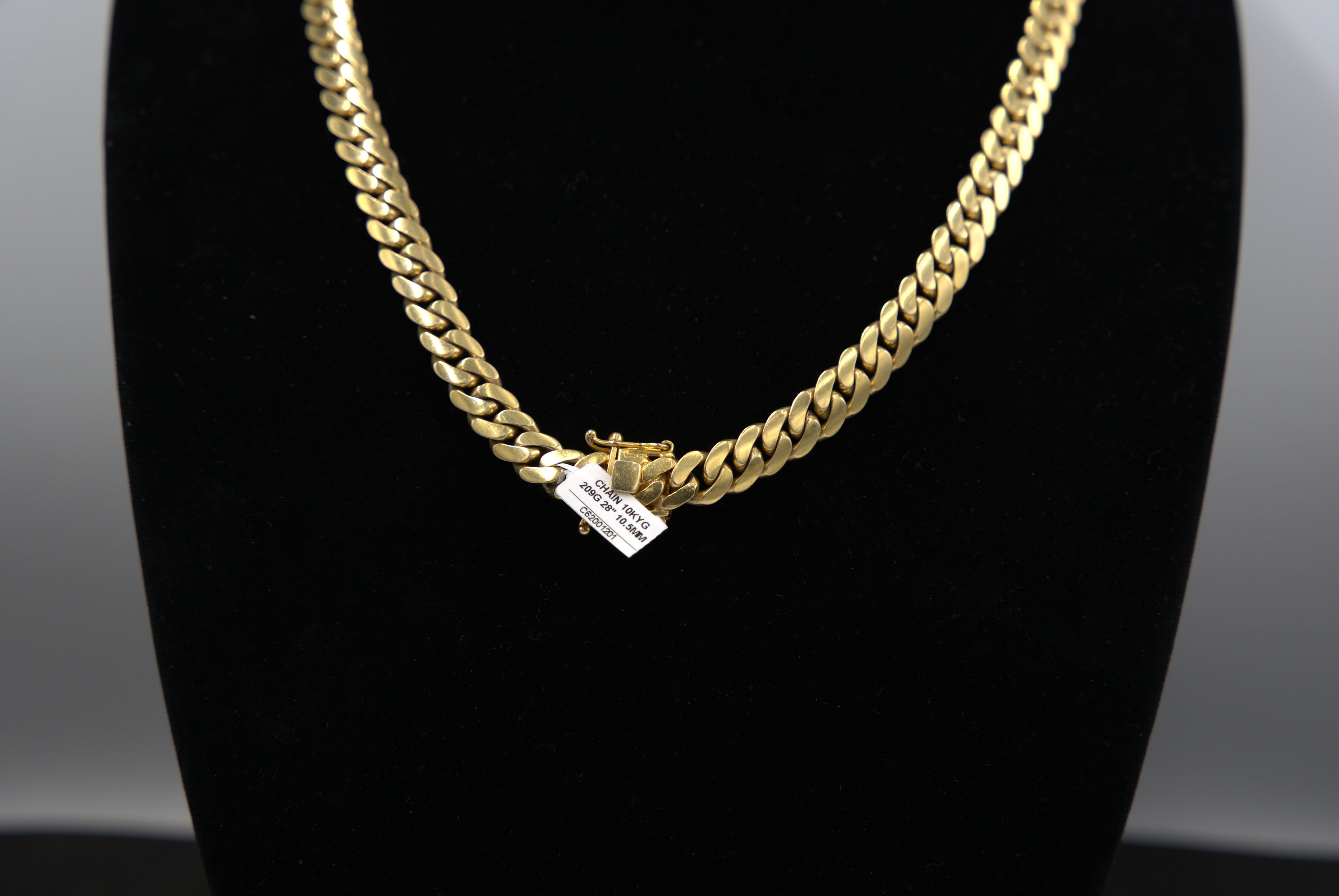 Gold chain necklace on a black mannequin bust with a neutral background