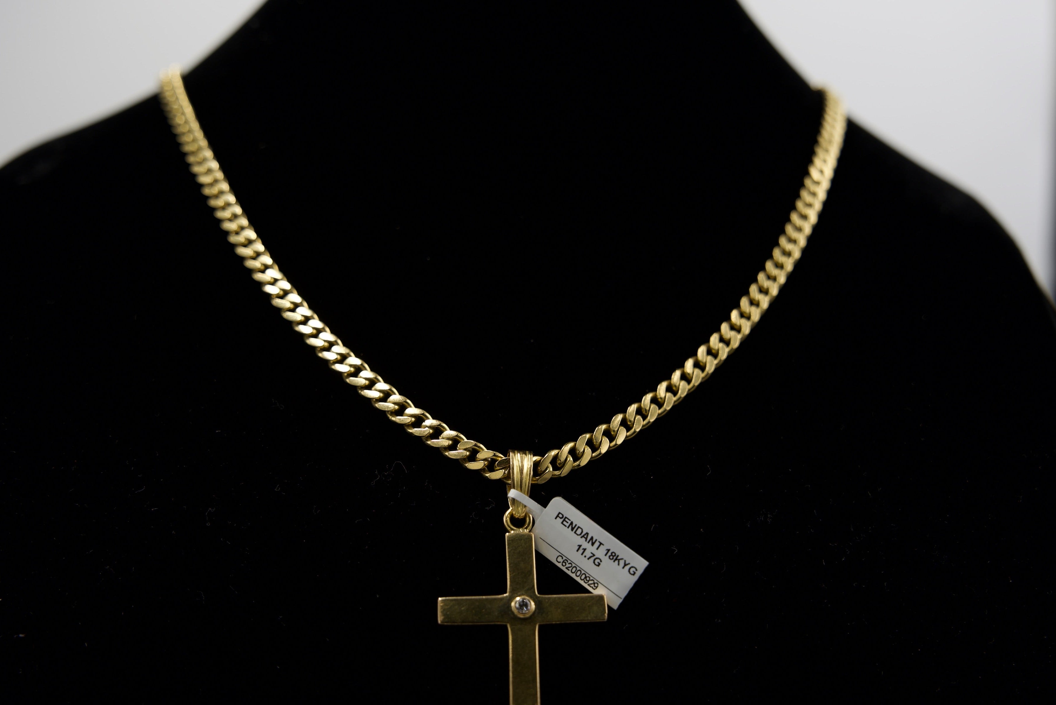 Gold chain necklace with a cross pendant on a black background