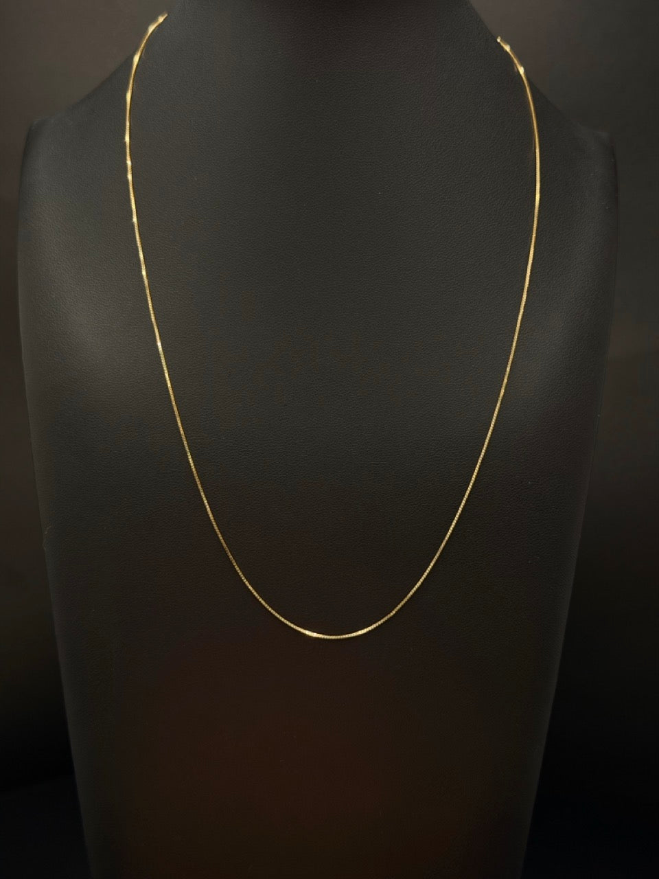 14K yellow gold snake chain measuring 18 inches long and approximately 1mm wide, weighing 7.4 grams, displayed on a black jewelry bust.
