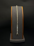 14K yellow gold diamond tennis bracelet measuring 7 inches long and weighing 14.6 grams, featuring a row of sparkling diamonds displayed on a jewelry stand.