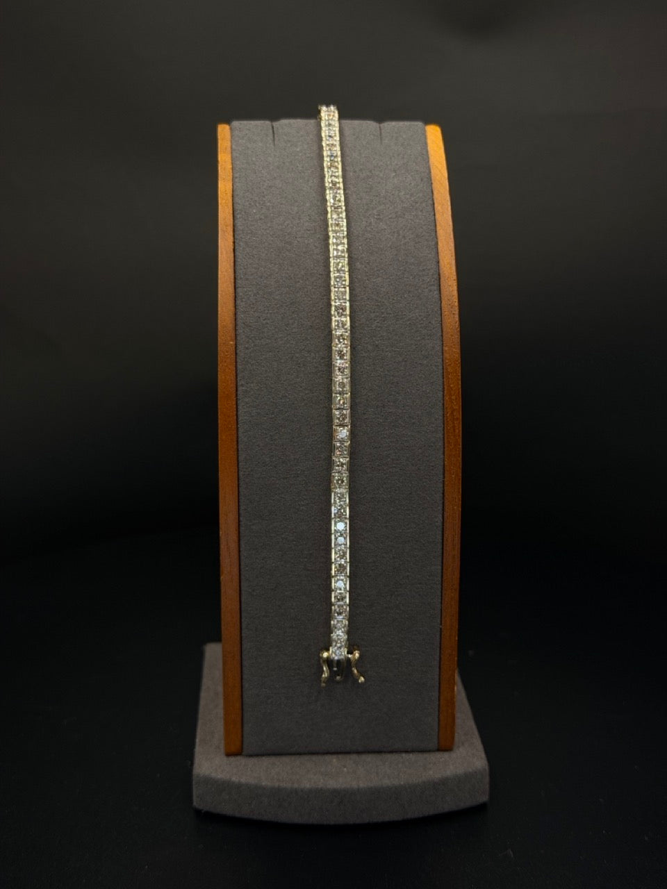 14K yellow gold diamond tennis bracelet measuring 7 inches long and weighing 14.6 grams, featuring a row of sparkling diamonds displayed on a jewelry stand.